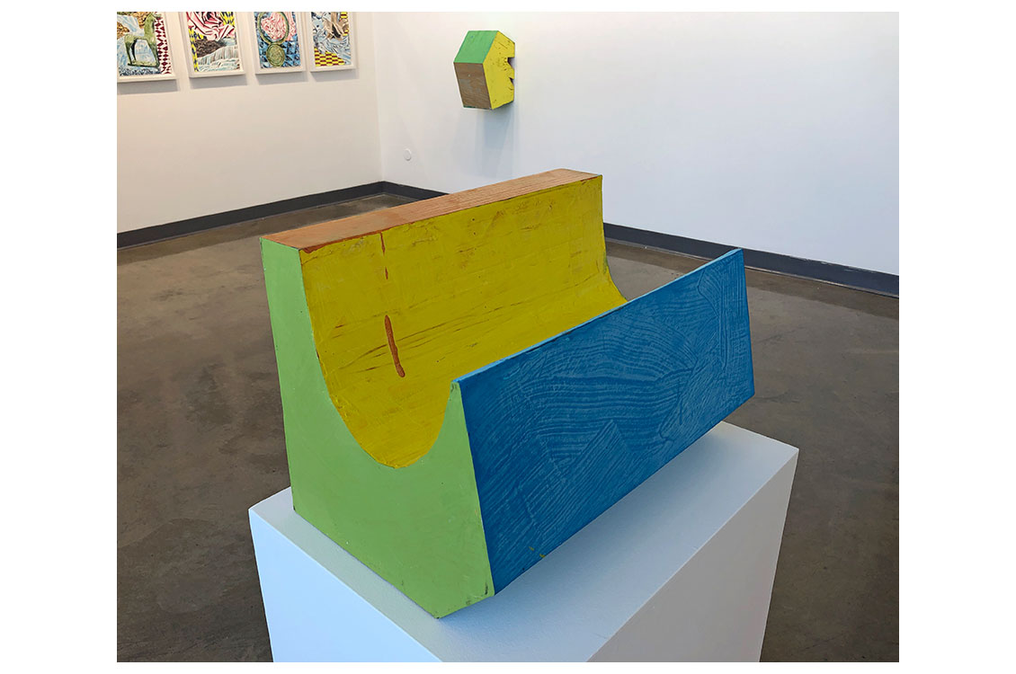 Wood sculpture on display, painted yellow, green, and blue
