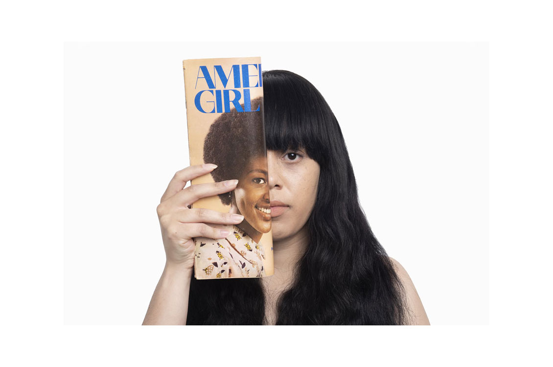 Photograph of woman holding a magazine up that covers half her face