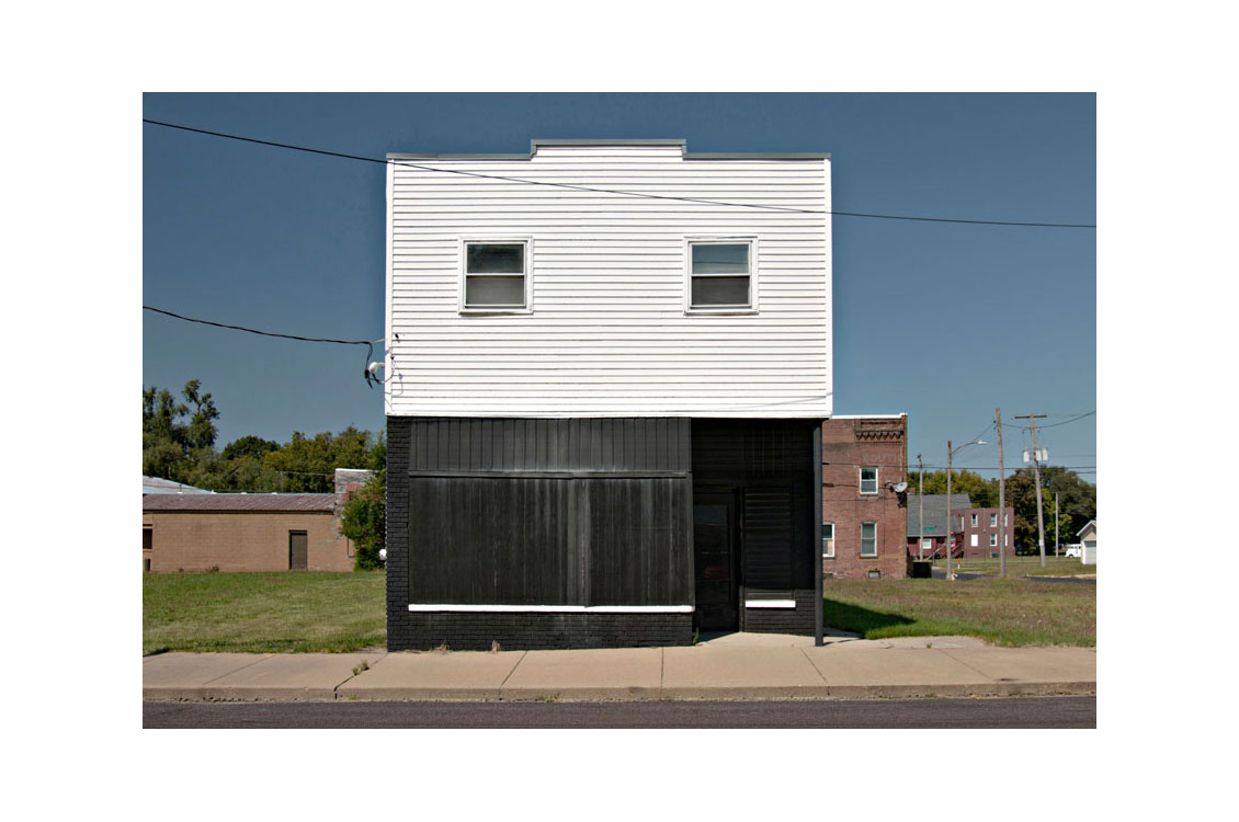 photograph of a black and white buildinging in a suburban or rural area