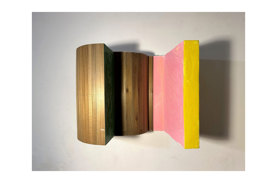 abstract wood sculpture with gold, pink, and yellow paint