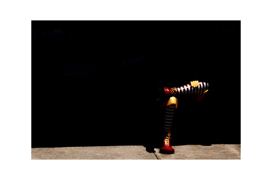 photograph of a clown statue almost entirely in shadow, with only the legs visibile