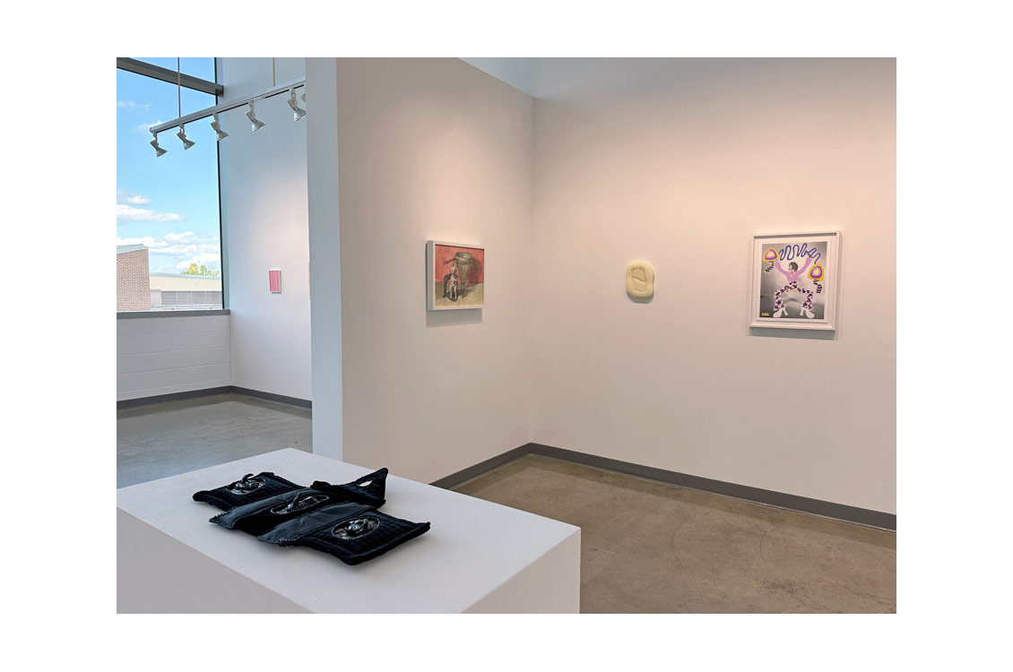 installation view with sculpture in foreground and paintings hung on wall in background