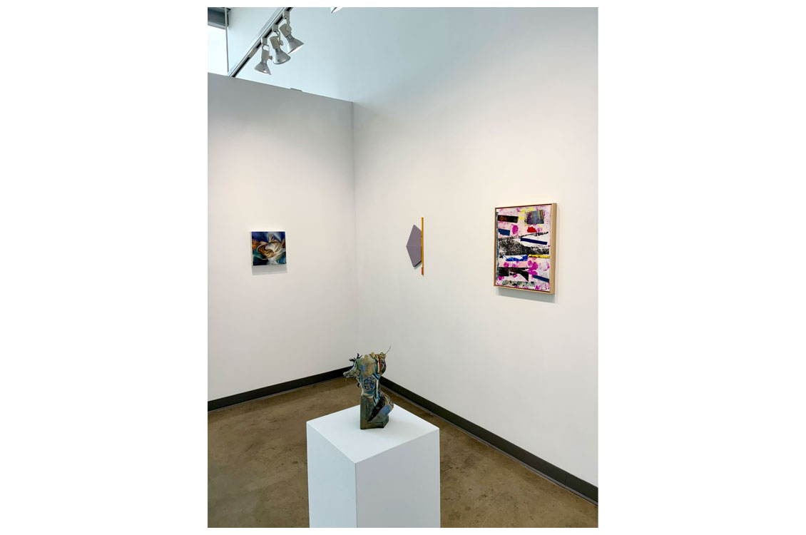 Gallery corner with three small framed artworks and a ceramic bust sculpture on a white pedestal.