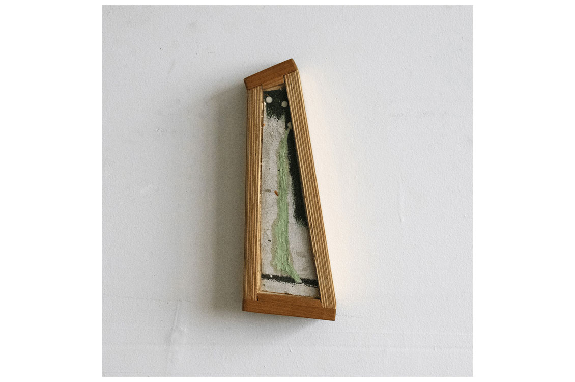 Tall, narrow wall sculpture in a wood frame with green and black textured layers.