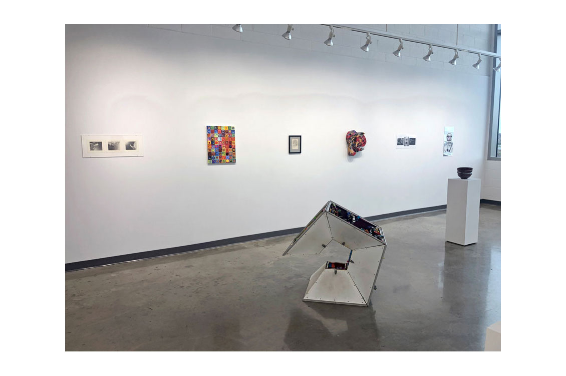 art gallery interior with pentagon sculpture in center and paintings on wall