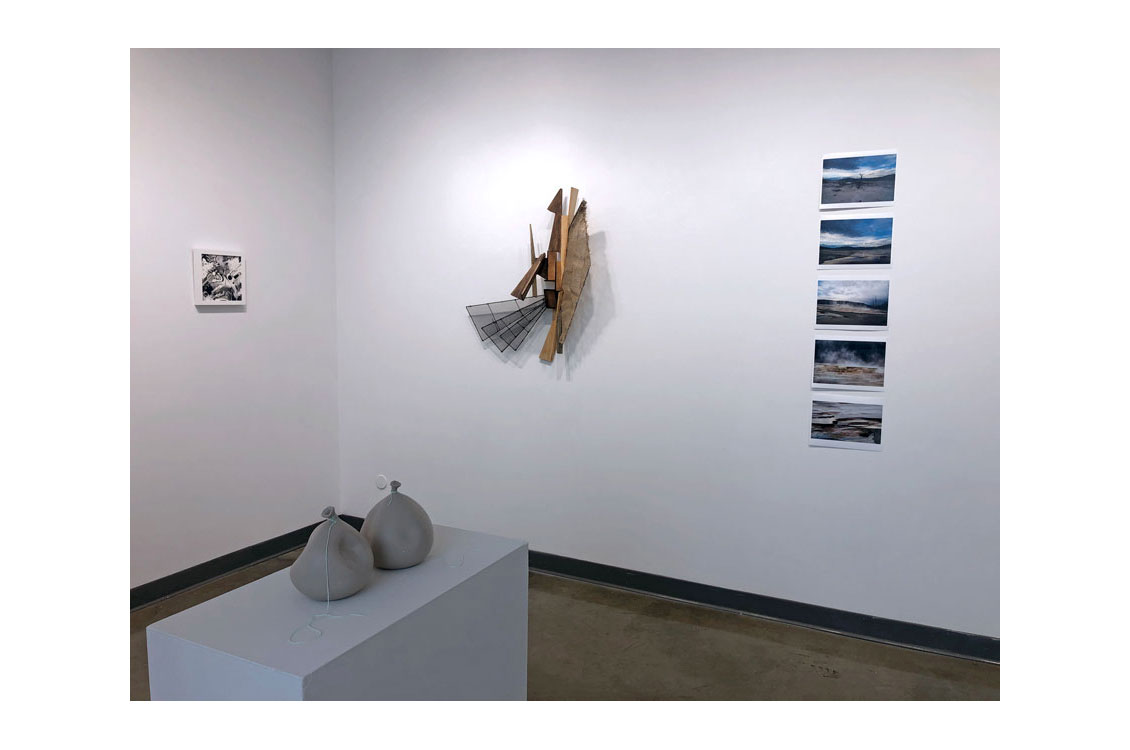 gallery interior with two pots on display, 3d sculpture and photographs on wall