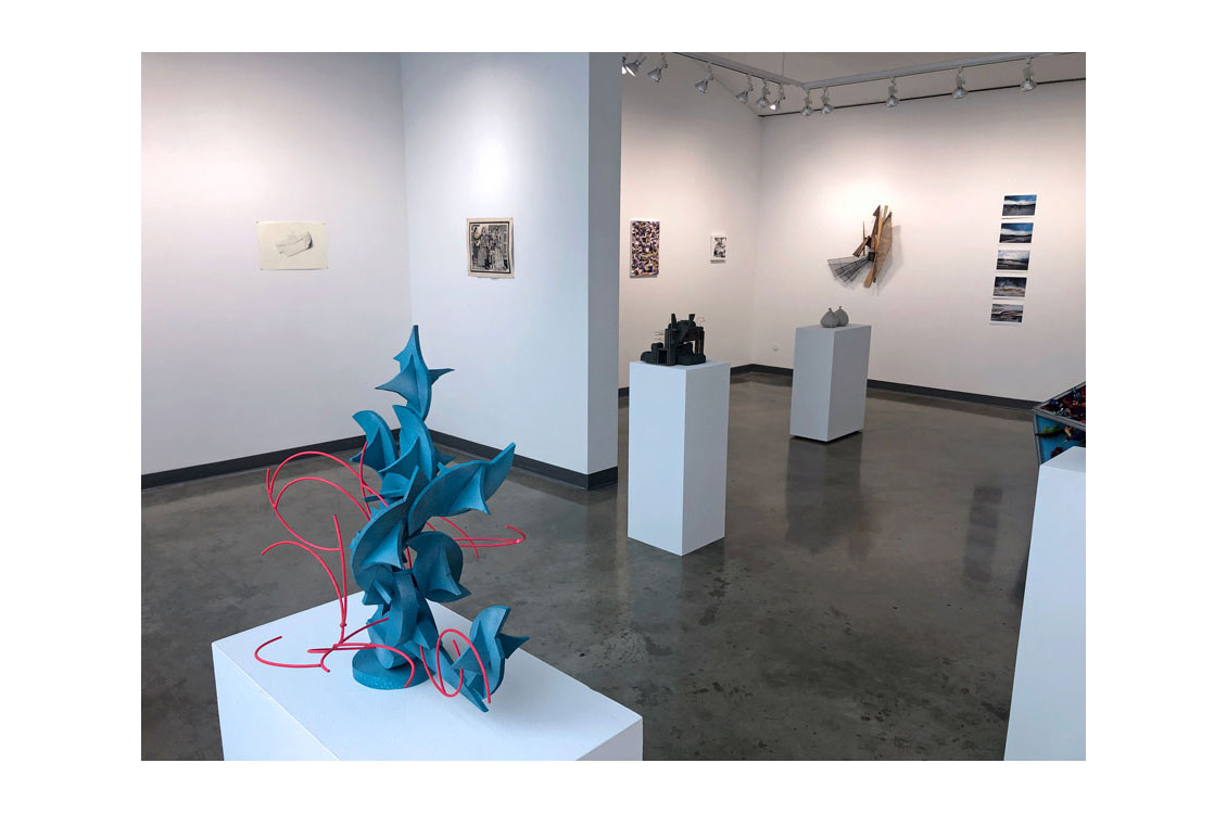 interior gallery view with sculptures in center and paintings on wall