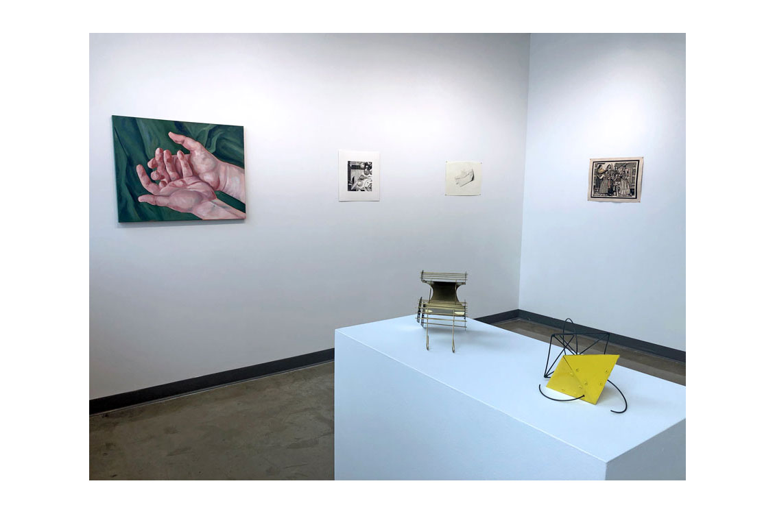 interior gallery view, with two sculptures on table and paintings on wall