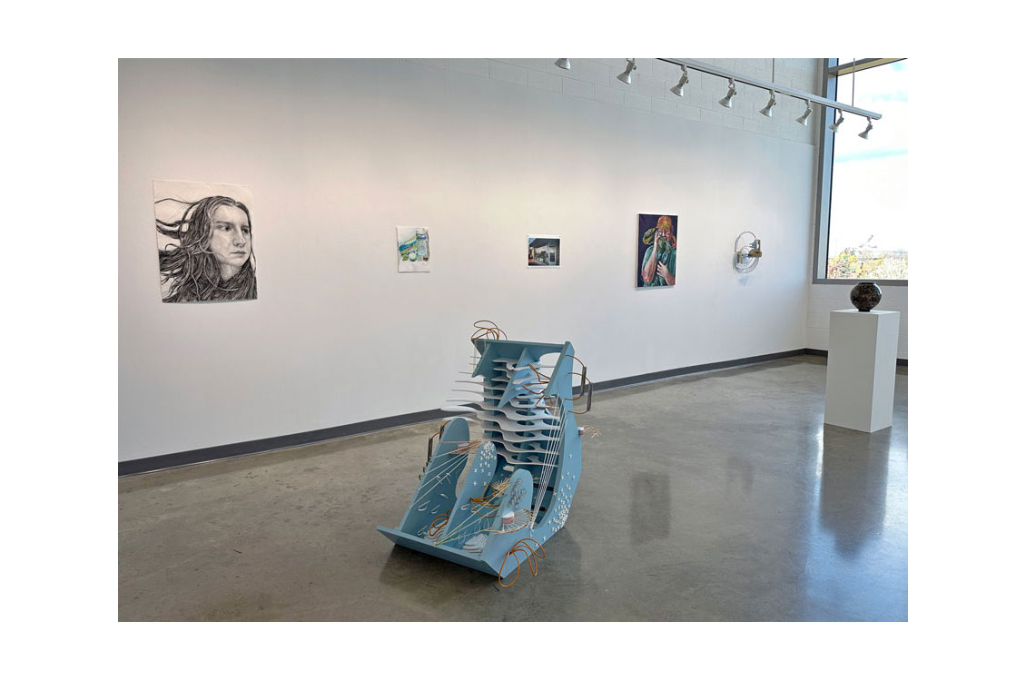 interior gallery view of exhibition with paintings on the wall and a sculputre on the floor