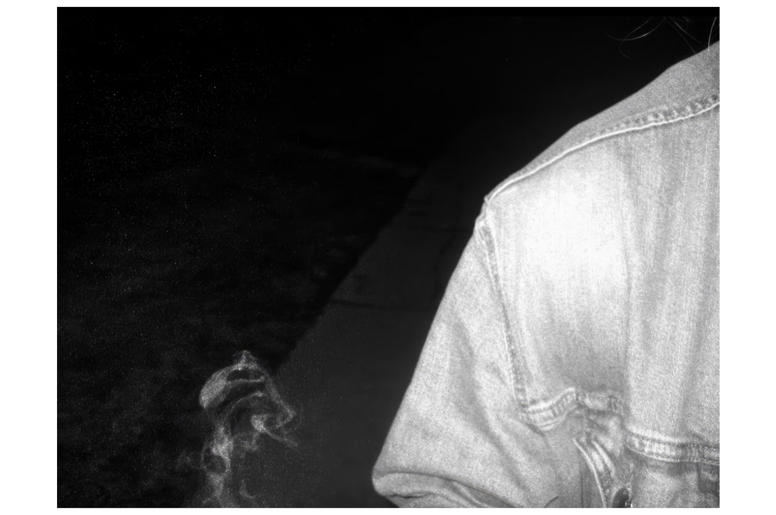 black and white photograph of a shoulder wearing a jean jacket and smoke