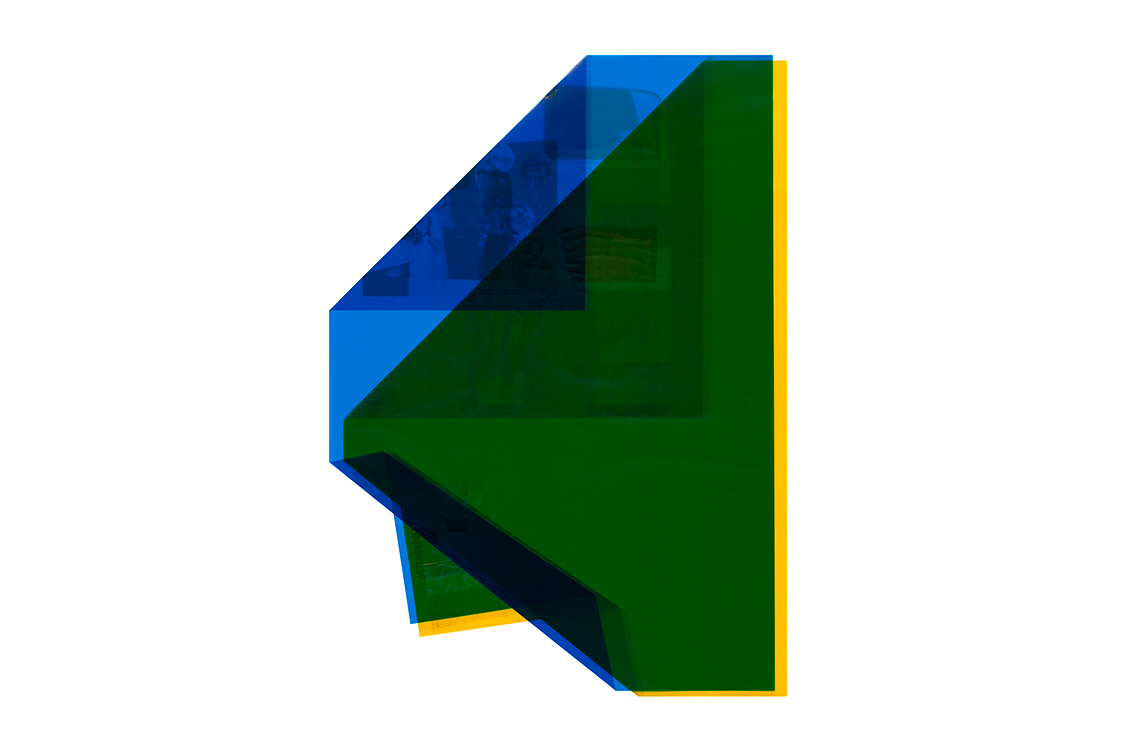 Transparent blue and yellow shapes overlap to form a large green shape.  Shadows of photographs can be seen in the background.