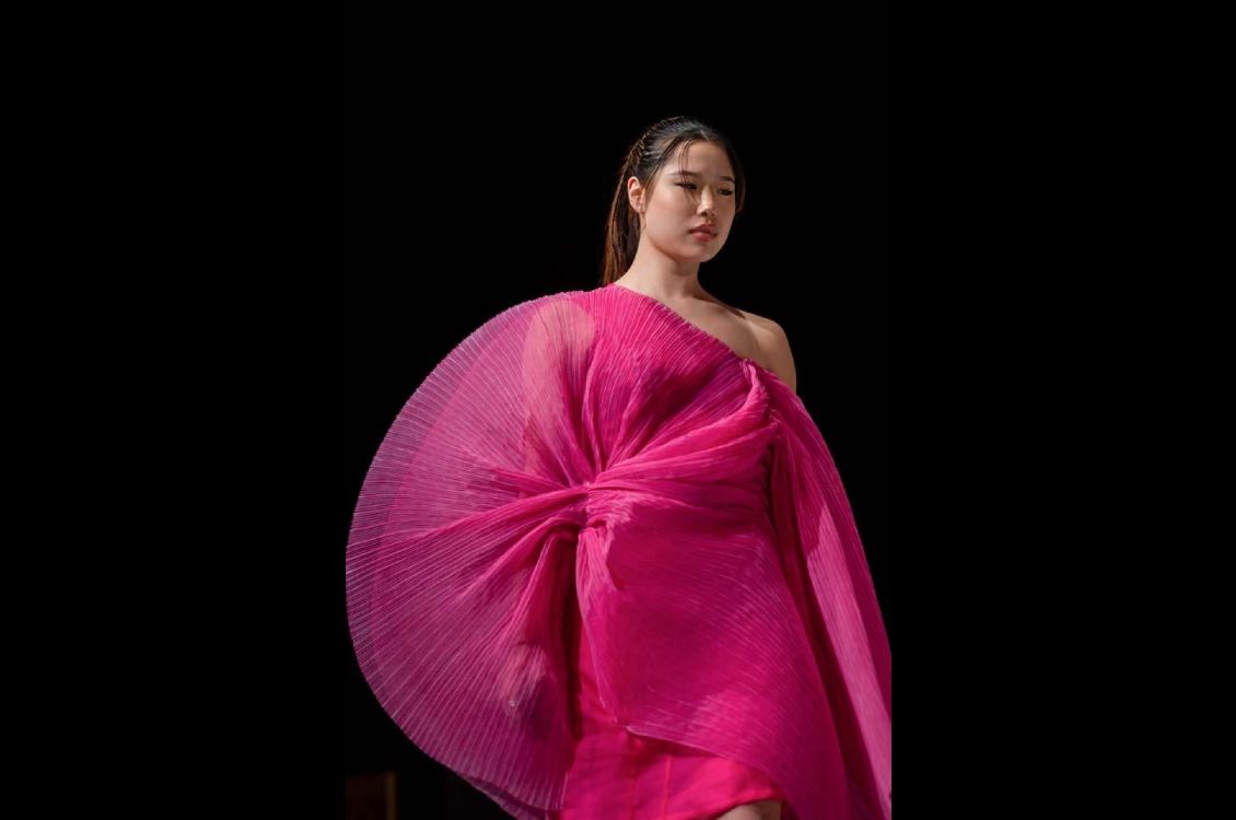Female model wearing a gauzy hot pink off-shoulder dress