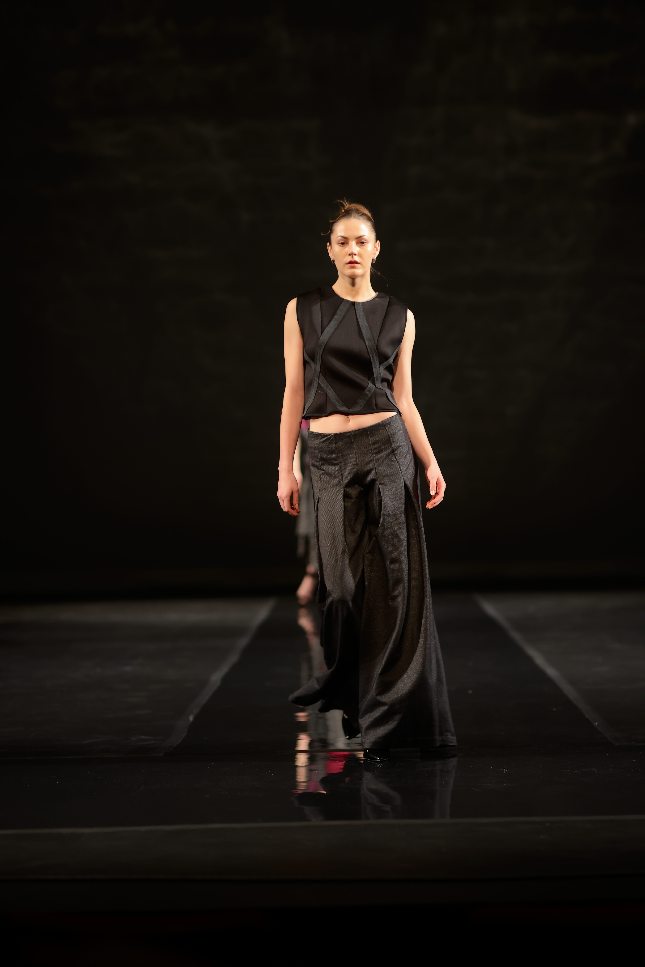Model walking down runway in a all black two-piece dress.