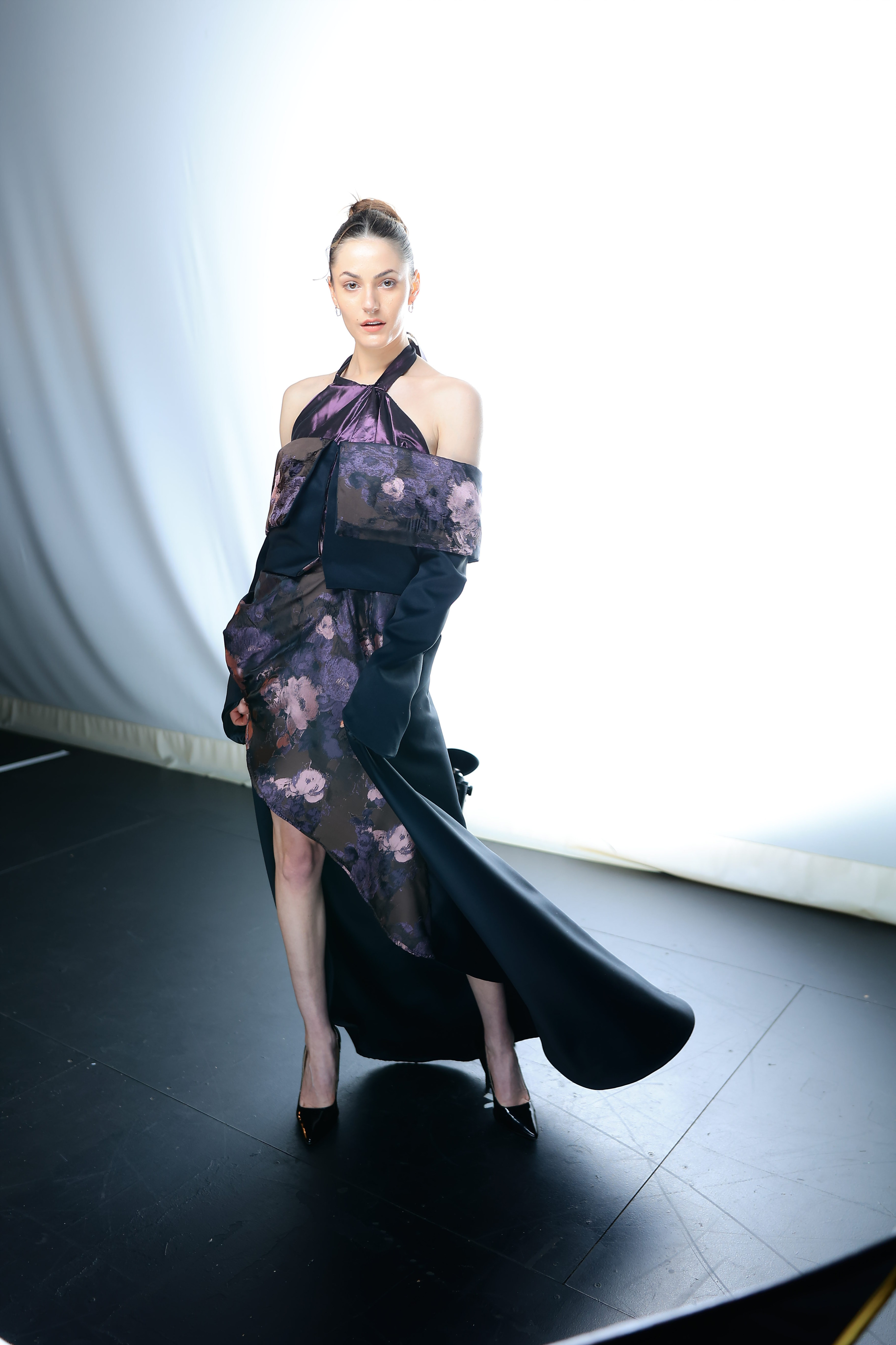 A model dress in a purple and black floral dress, posing for photos