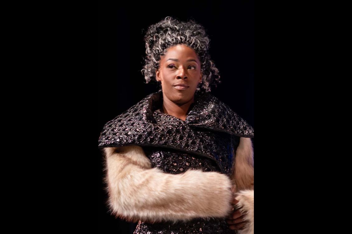 Woman wearing a textured black leather jacket with cream fur sleeves.