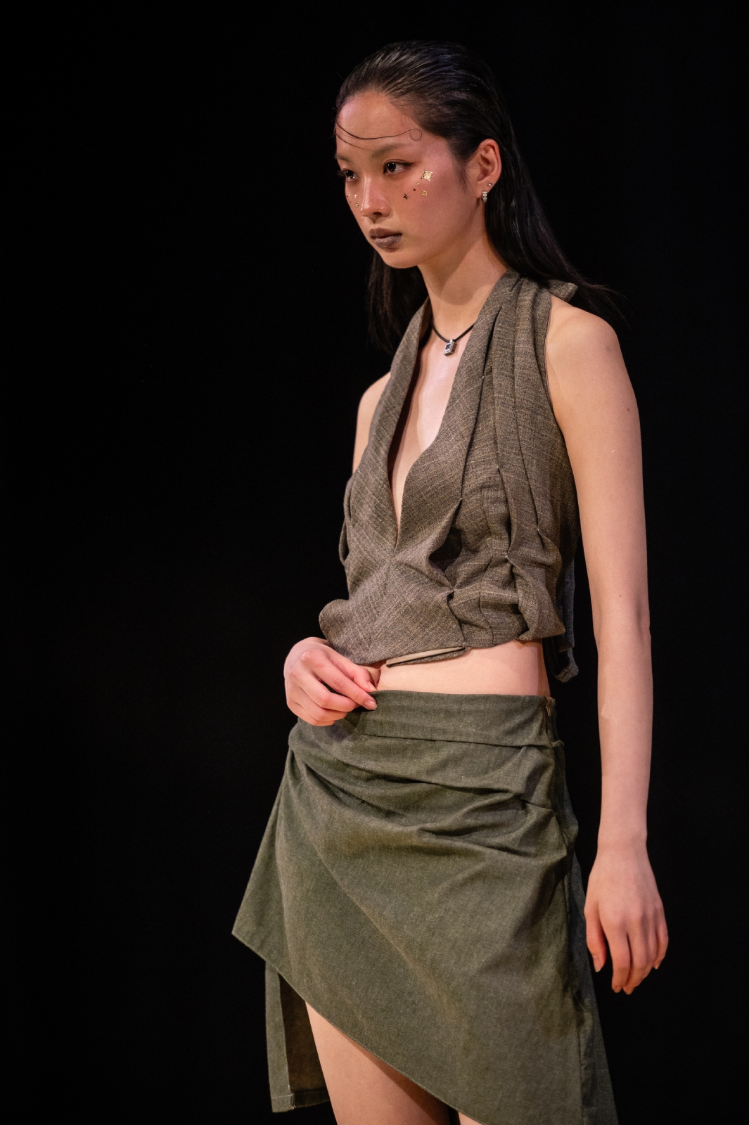A model striking a chic pose as she models a matching gray halter top and skirt with textured stitches