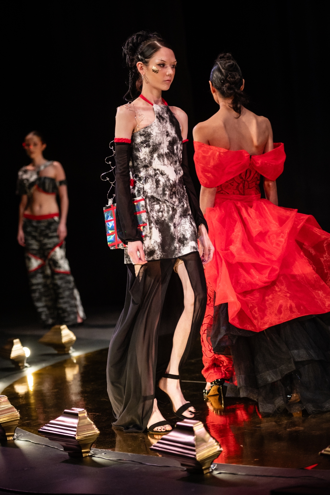 Two models walk past each other on the runway