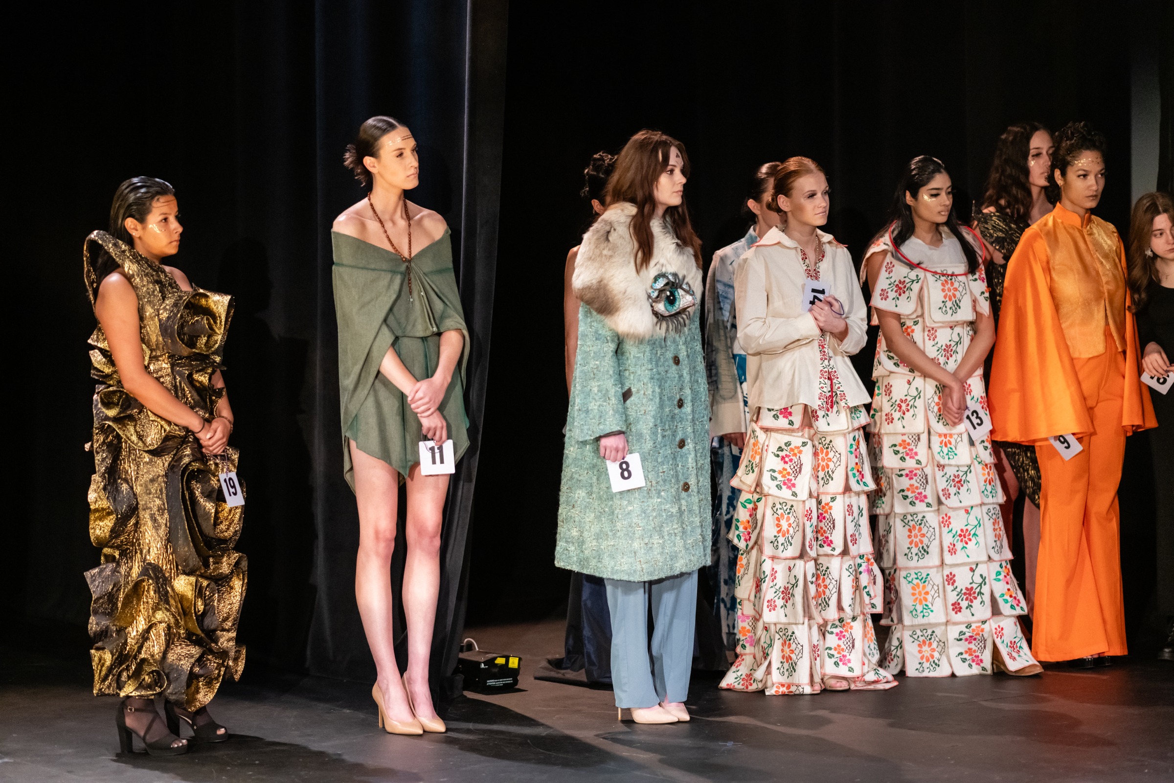 A group of models lined up and listening to instructions for what order to walk the runway in