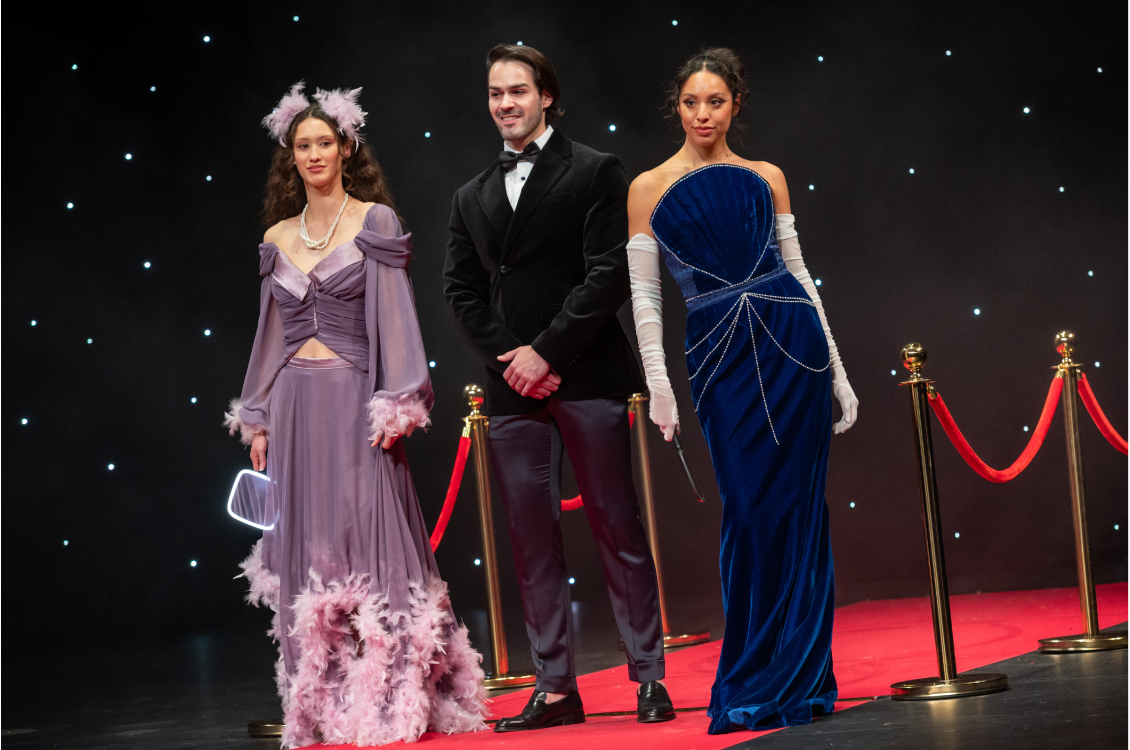 two female models and a male posing on runway