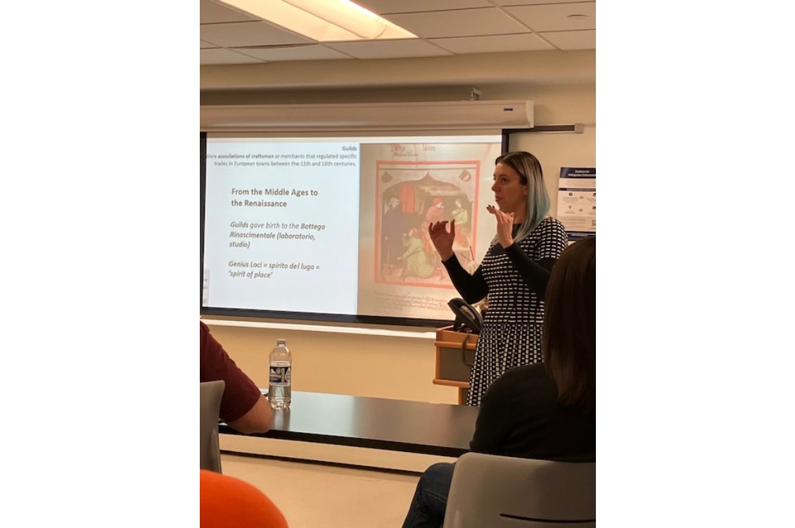Dr. Lelaine Rigatto standing in front of a projection of a slideshow in a classroom
