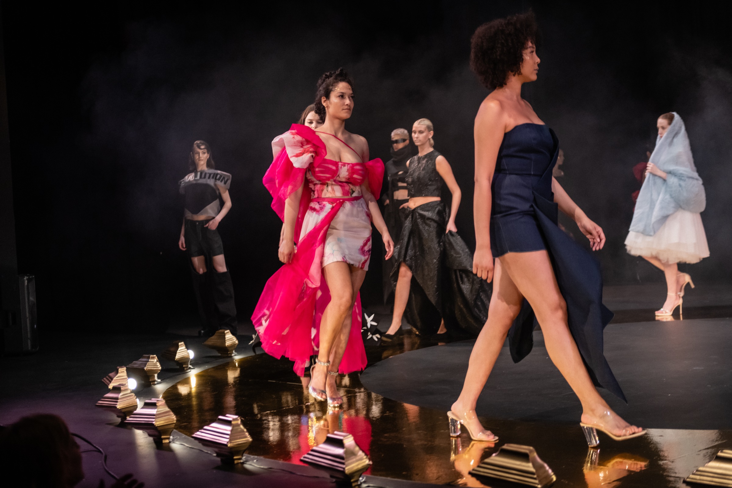models walking along the golden catwalk, flaunting their futuristic outfits