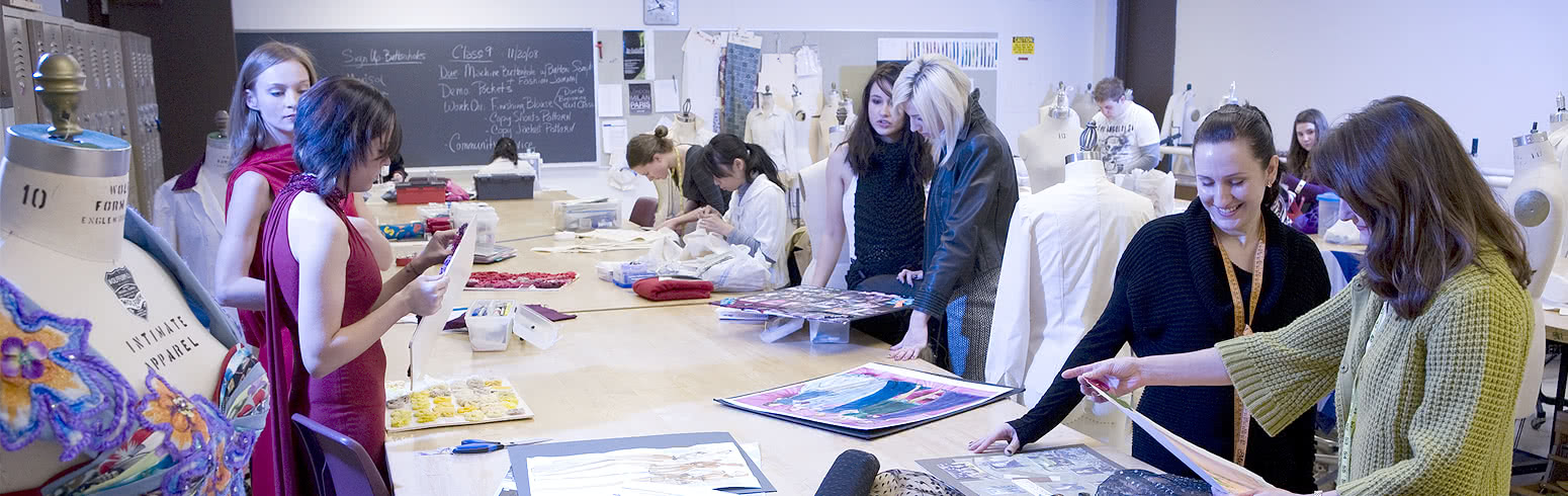 Students work in the fashion design laboratory, cutting fabric, measuring and fitting clothes on dress forms