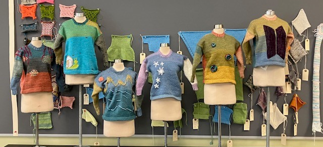 Colorful hand-knitted sweaters and swatches on display in a textile studio.