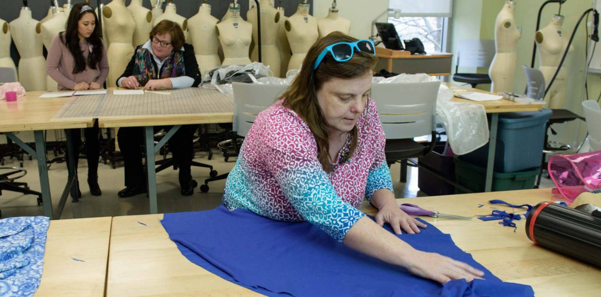 Student working on fabric with student and professor in the background