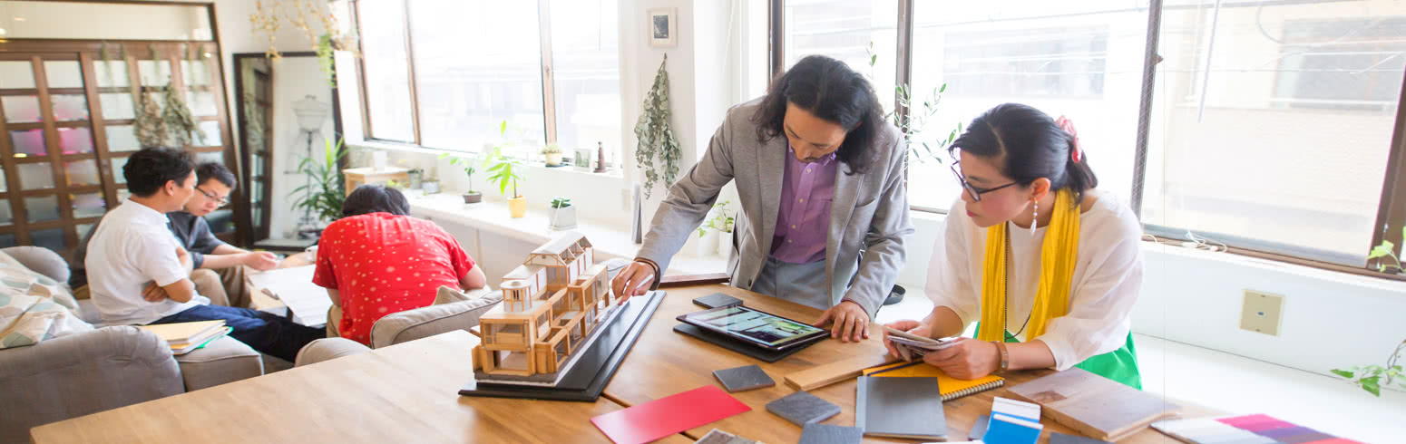 Two interior designers examining a small-scale wooden model of a home.