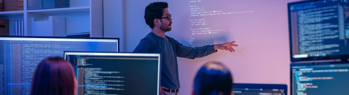 A deep learning professional showing programmers example code on a whiteboard.