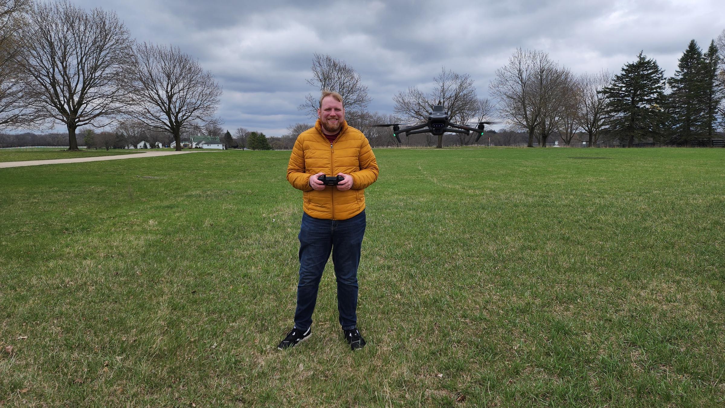 A GIS/Drone Technology student standing in a field and holding a drone remote