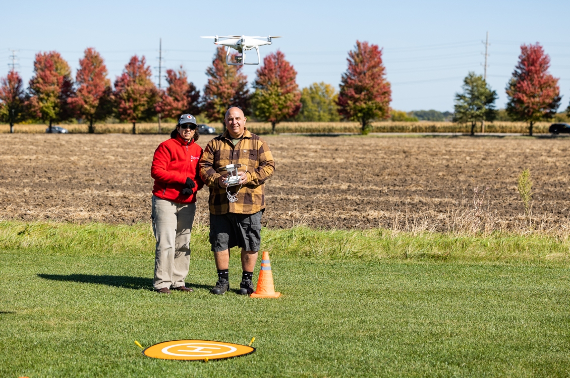 A student flies a drone outside with the help of an instructor.