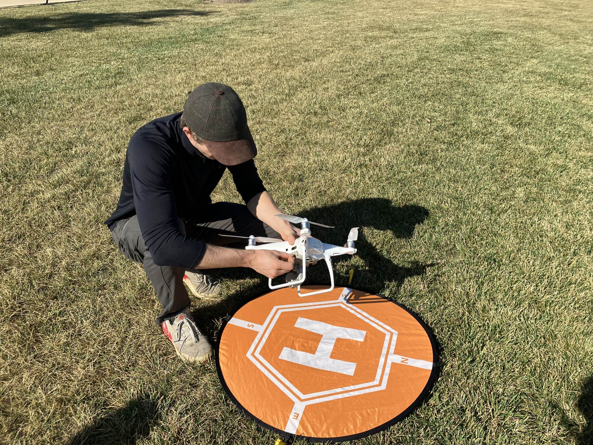 A GIS/Drone Technology student setting up a drone on an outdoor landing pad