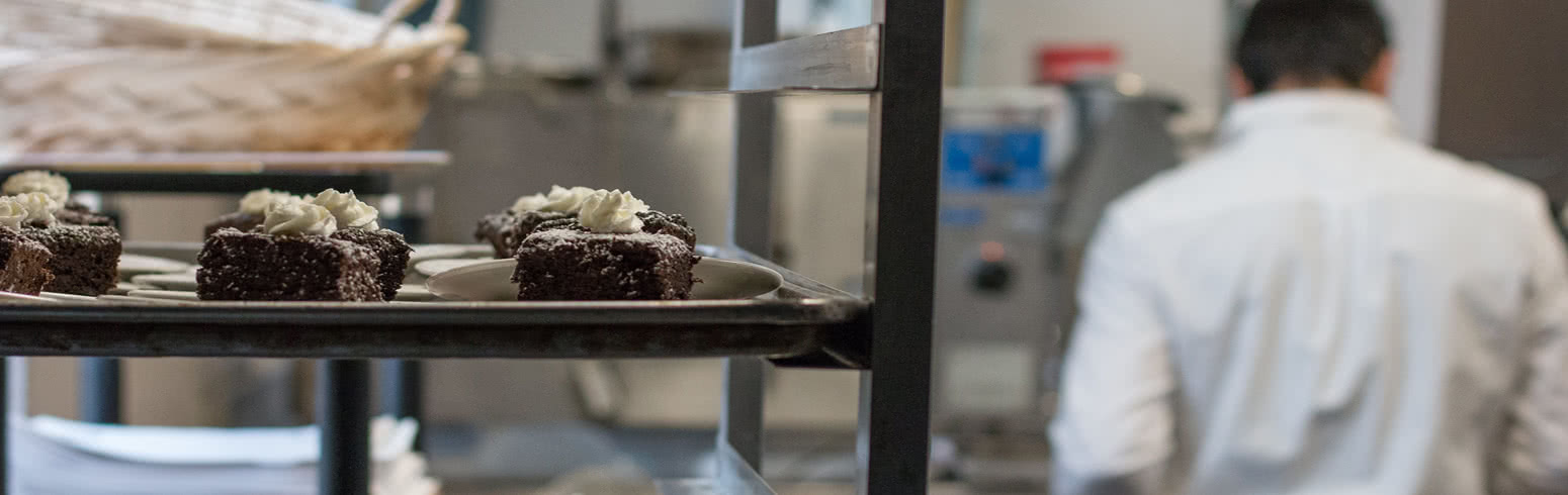 Brownies cool on a rack while a baker works in the background