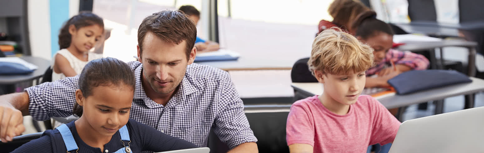 Teacher shows students how to use the computer 