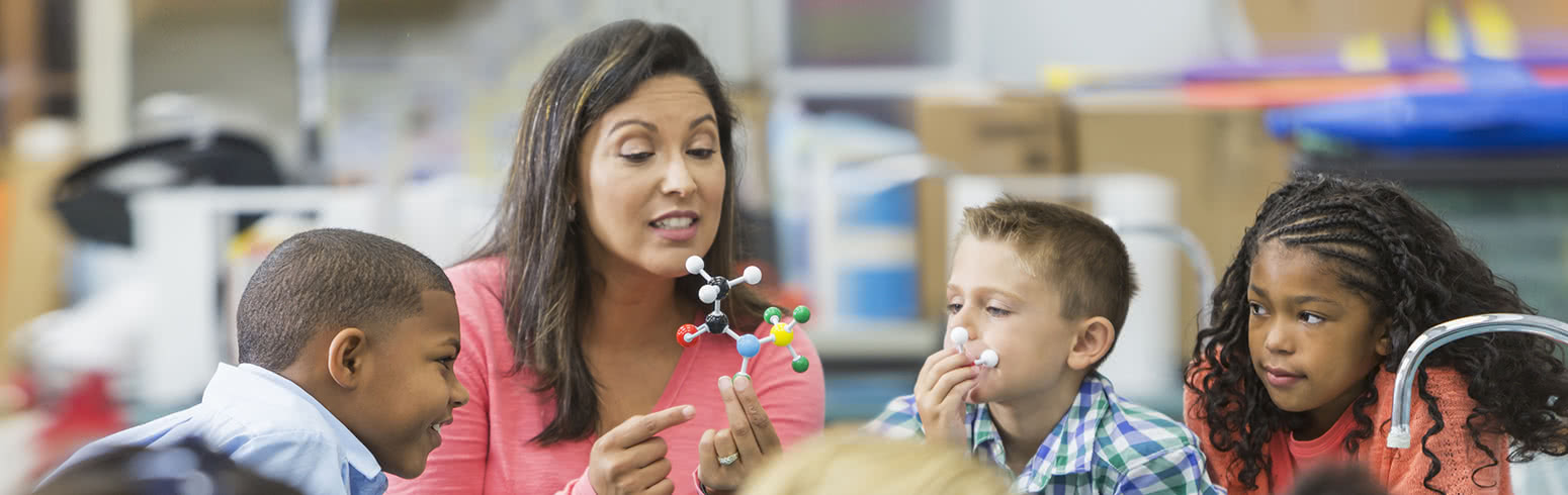 Paraprofessional educator presenting a scientific lesson to a small class of young students.