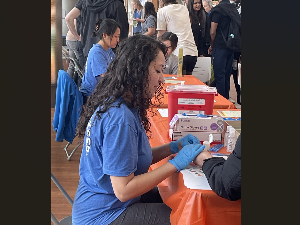 Student performs a test on a patient at a health event