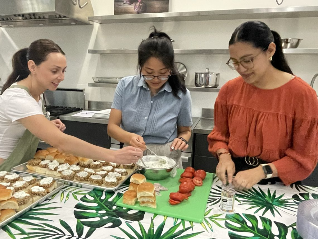 Students stir a creamy sauce and layer it onto sandwiches