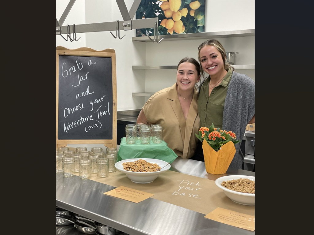 Students pose with bowls of nuts, jars and a potted flower