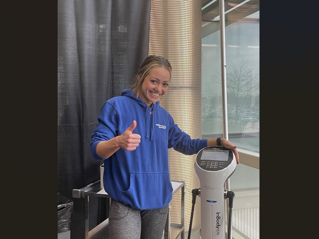 Student poses with a large body weight scale