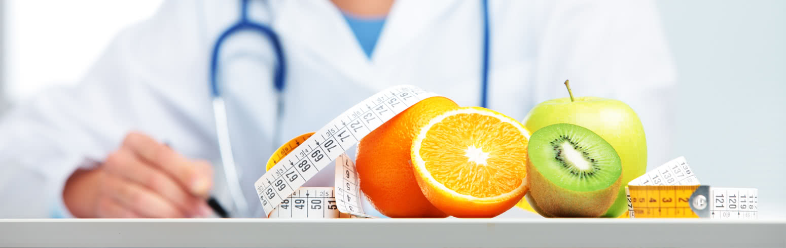 Registered nutritionist taking notes with sliced fruit on the table nearby.