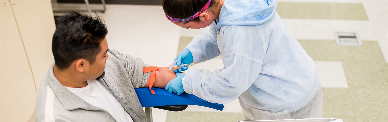 A student practices drawing blood from a patient in a phlebotomy class in the medical clinic on Harper College's campus in Palatine, Illinois.