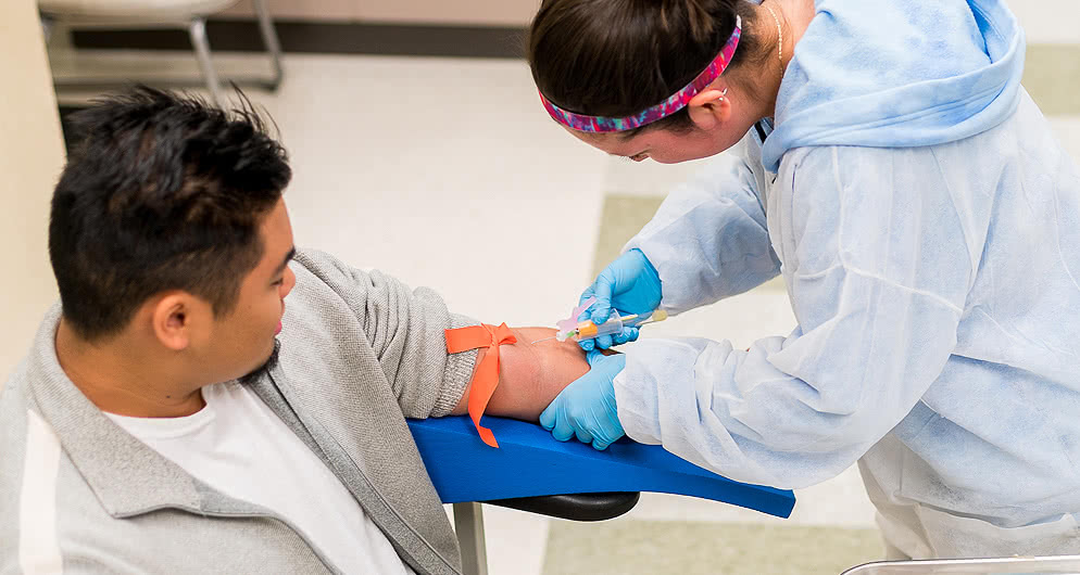A student practices drawing blood from a patient in a phlebotomy class in the medical clinic on Harper College's campus in Palatine, Illinois.