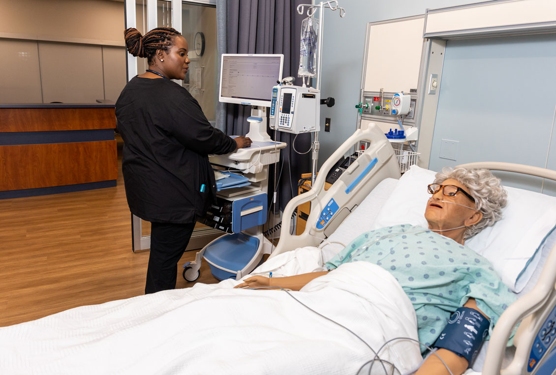 a student nurse checks on a dummy patient in a hospital bed