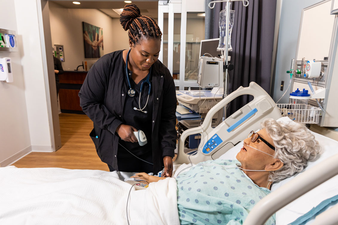 a student practices taking a dummy patient's pulse