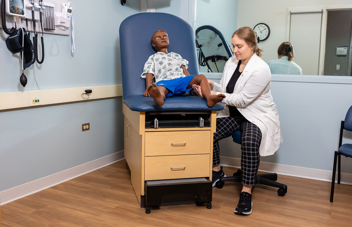 a student interacts with a child dummy in a simulation exam room