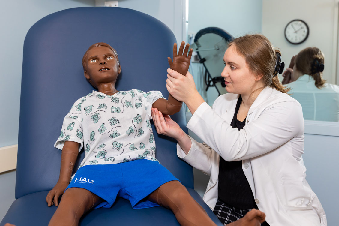 a student checks a child dummy's arm