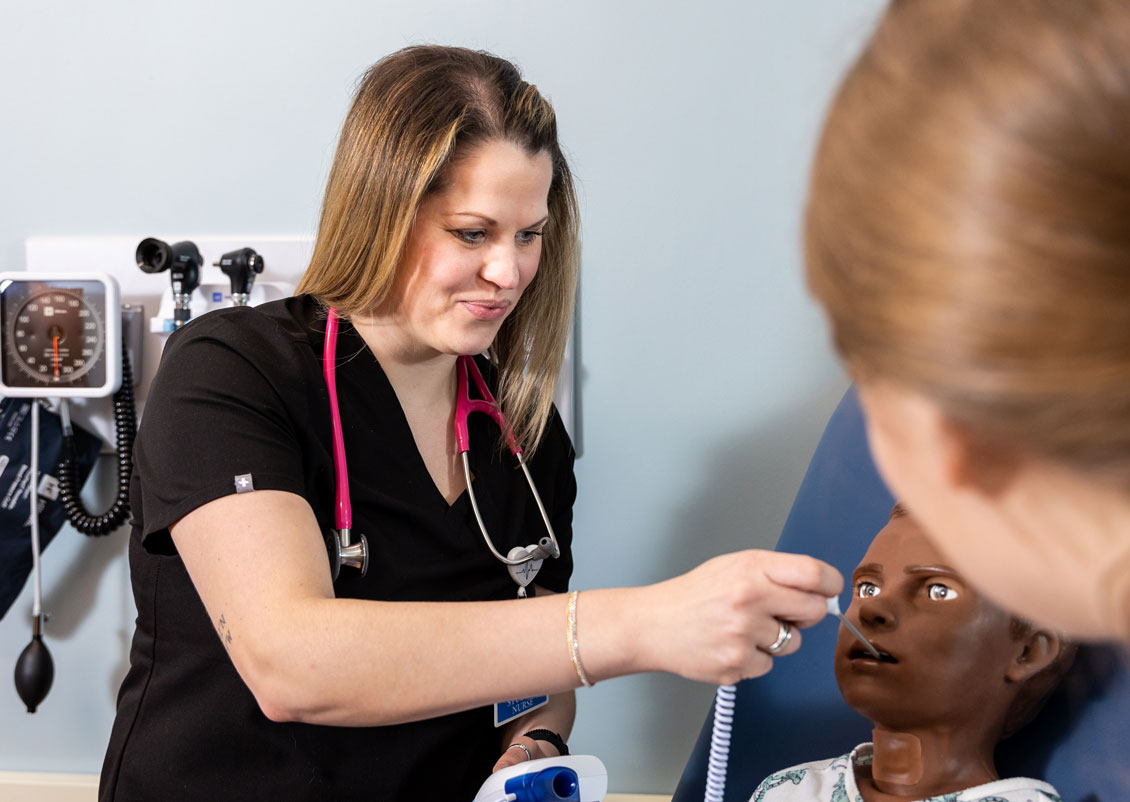 a student uses a medical instrument on a simulation dummy