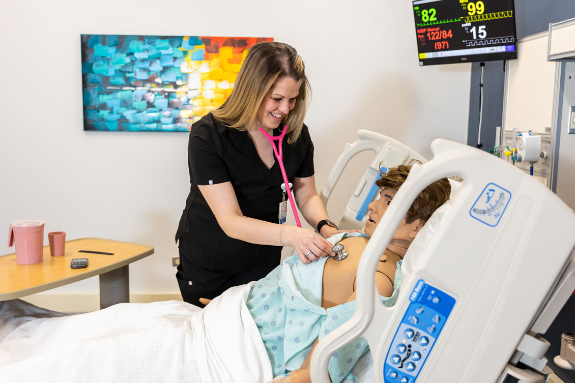 a student uses a stethoscope on a simulation dummy