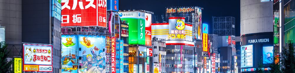 colorful signs lit up on a street in Japan at night